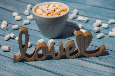 Wooden word love with heart romance with white coffee cup of hot chocolate and small marshmallows