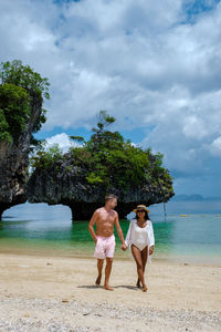 Full length of woman standing at beach against sky