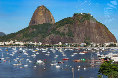 Boats moored in sea against sugarloaf mountain seen from glass