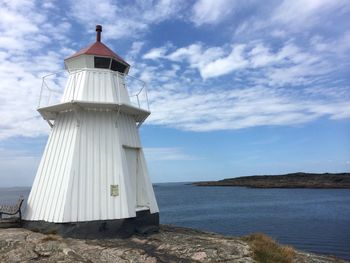 Lighthouse by sea against sky