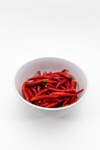 Close-up of red chili peppers in bowl against white background