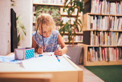 Schoolgirl doing homework. elementary student learning, drawing pictures, doing puzzles at desk