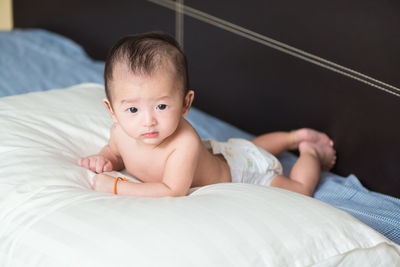 Portrait of cute baby girl relaxing on bed at home