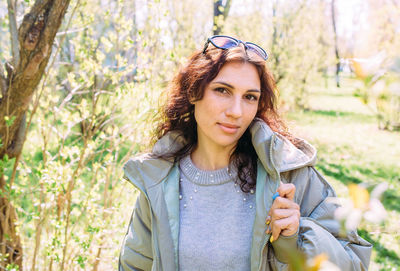 Portrait of young woman standing against trees