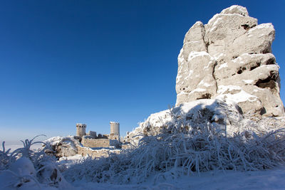 Snow covered land against clear blue sky