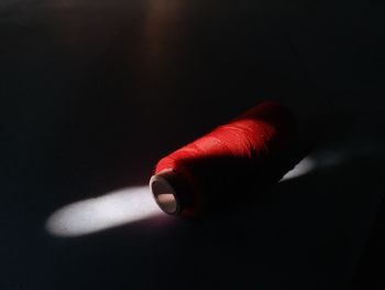 Close-up of hand holding red light over black background