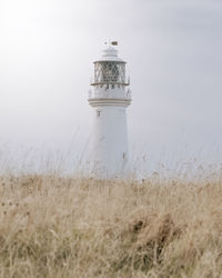 Lighthouse on field against sky