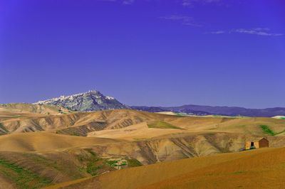 Scenic view of desert against clear blue sky