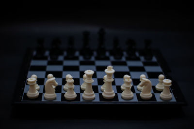 Close-up of chess pieces on board against black background