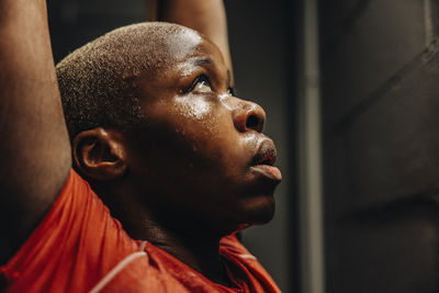 Female athlete looking up with arms raised while working out in gym