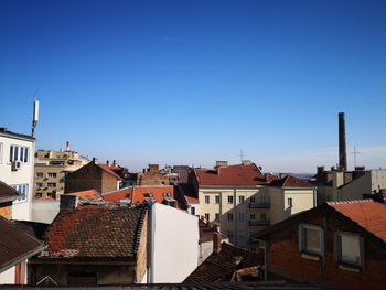 Buildings in city against clear blue sky