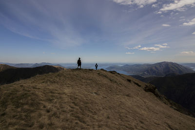 Hikers standing on mountains against sky