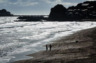 People standing on beach by sea against sky