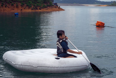 Boy sitting in boat on lake