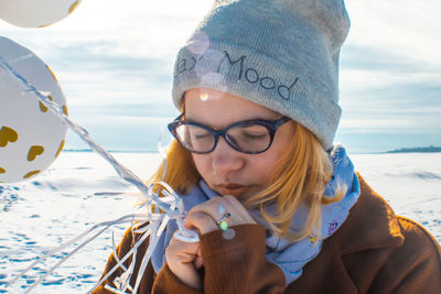 Close-up of woman with warm clothing holding balloons