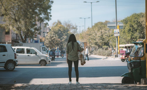 Rear view of woman walking on road in city