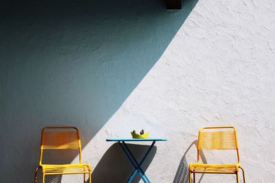 Empty chairs and table against the wall