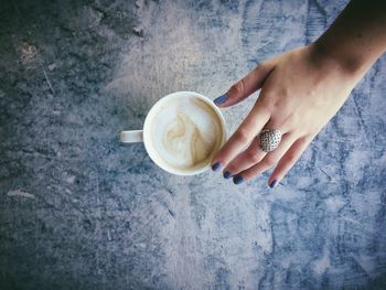 High angle view of young reaching for cup of coffee