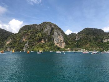 Sailboats on sea by mountains against sky