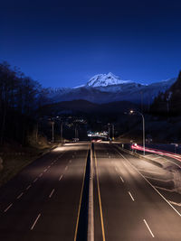 Road leading towards mountains against sky at night