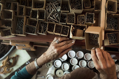 Hands of senior female sales clerk removing nails from cardboard box in hardware store