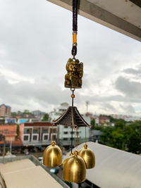 Bell hanging outside building against sky in city