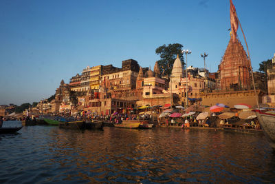 Boats in canal amidst buildings against clear sky