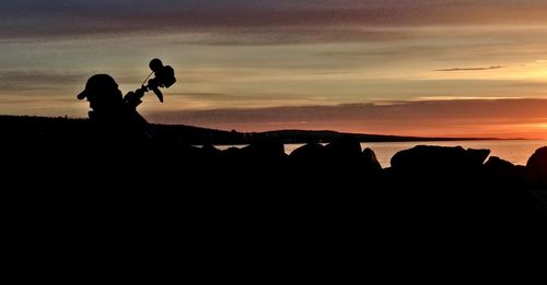 Silhouette people at beach against sky during sunset