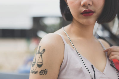 Midsection of woman with tattoo standing outdoors