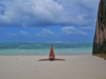 Man relaxing on beach against sky