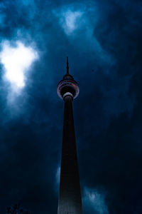 Low angle view of fernsehturm against cloudy sky at dusk