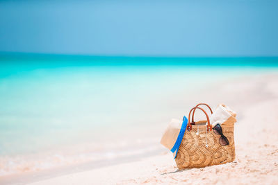 Wicker basket on sand at beach against sky