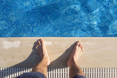 Low section of man standing by swimming pool