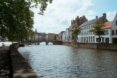 Arch bridge over river amidst buildings against sky