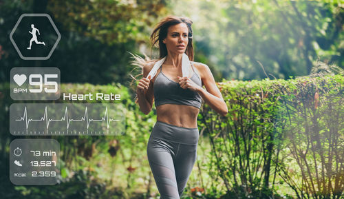 Girl running in the park. runner check heartbeat, steps and distance. technology, health concept.