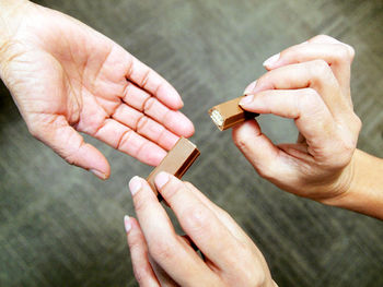 Cropped hands of person sharing chocolate with friend