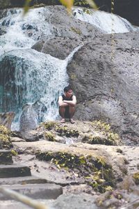 Rear view of man sitting on rock