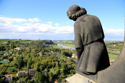 Rear view of woman statue on field against sky