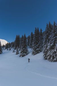 People skiing on snow covered field against sky