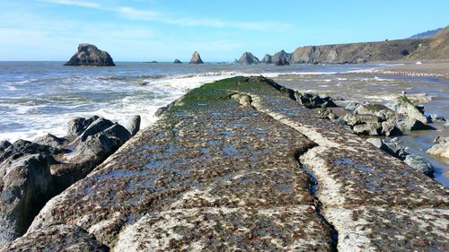 Scenic view of jutting breakwall where river meets sea against sky