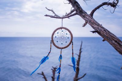 Close-up of decoration hanging over sea against sky