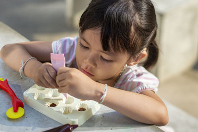 Close-up of cute girl playing with childs play clay at table outdoors