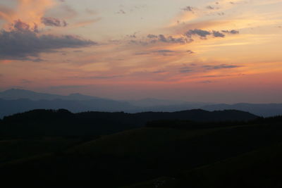 Scenic view of silhouette mountains against orange sky