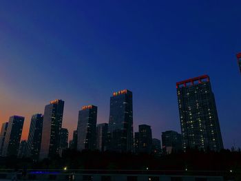 Illuminated buildings against blue sky at dusk