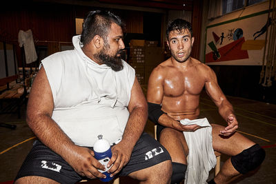 Midsection of shirtless man sitting on floor