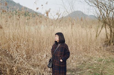 Woman looking away while standing on field