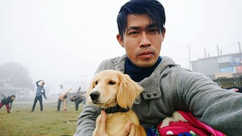 Young man holding dog at park