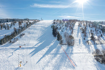 Aerial photo shows an inviting slope for skiing. the sun is shining. only 2 people are walking.