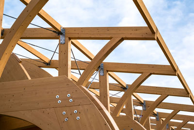 Detail of a modern wooden architecture in glued laminated timber on a blue cloudy sky