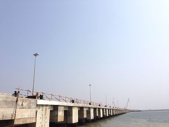 Low angle view of pier by sea against clear sky